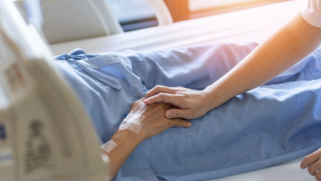 Pflegekraft für Hospiz- und Palliativpflege hält Patientenhand.